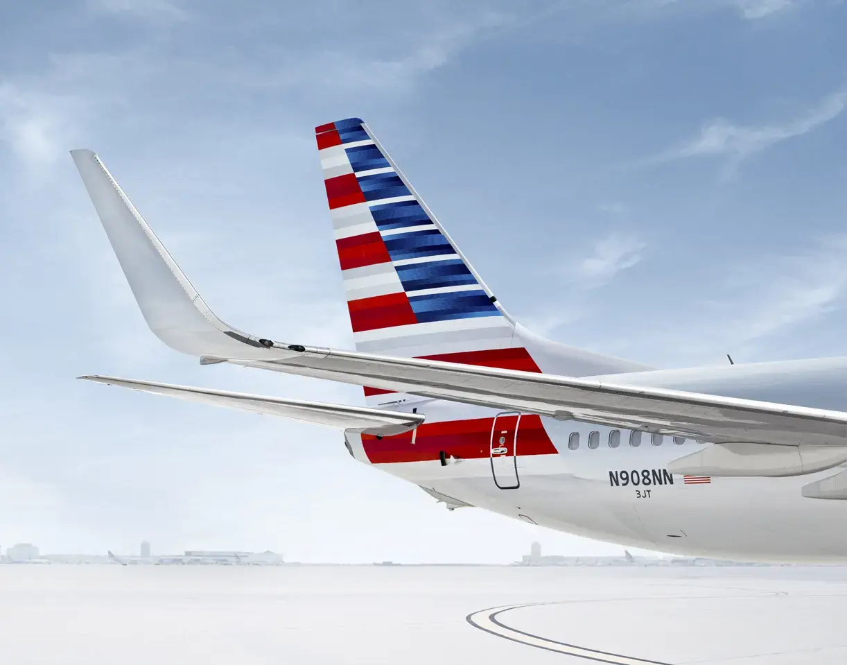 Close-up of an aircraft tail with red, white, and blue stripes, parked on a snowy tarmac.
